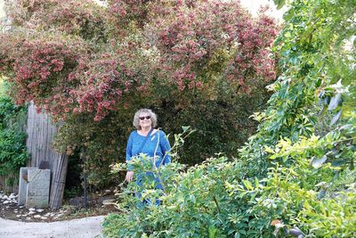 Portrait of young woman standing against plants