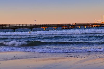 Scenic view of beach against clear sky during sunset