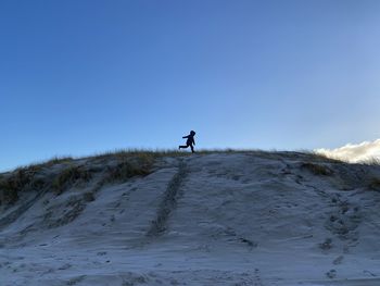 Man on snow covered land against sky