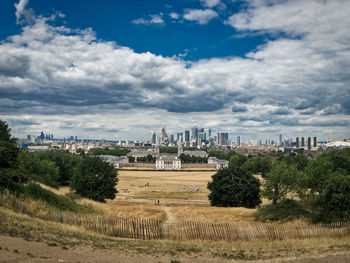 View of trees and buildings against cloudy sky