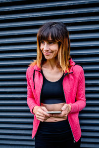 Portrait of female athlete posing with mobile phone