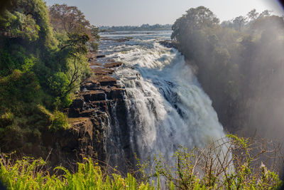 Scenic view of waterfall against sky