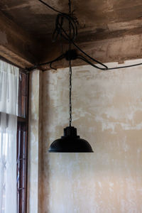 Low angle view of pendant light hanging on wall in building