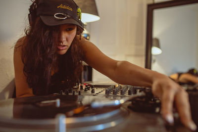 Close-up of fashionable young woman playing music at home