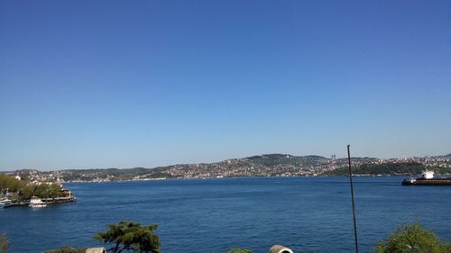 Boats in sea against clear blue sky