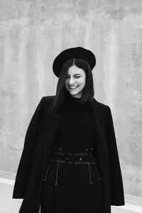 Portrait of a smiling young woman standing against wall