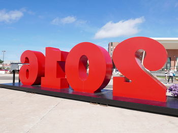 Red text on footpath against blue sky