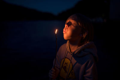 Boy blowing burning stick while standing in olympic national park at night