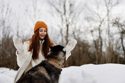 Portrait of woman with dog on snow covered field