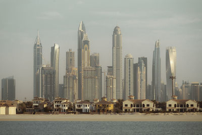 Sea by modern buildings against sky in city