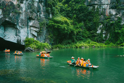 People on boat in river against trees