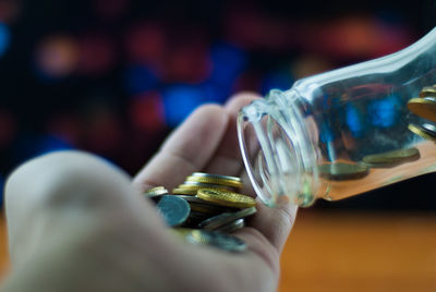 Close-up of person removing coins from bottle in hand