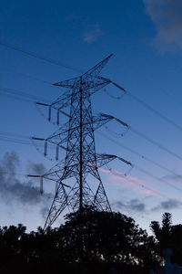 Low angle view of electricity pylon against cloudy sky