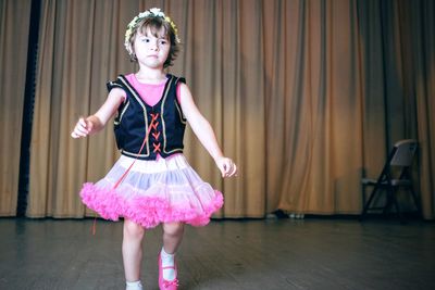 Girl performing against stage curtain