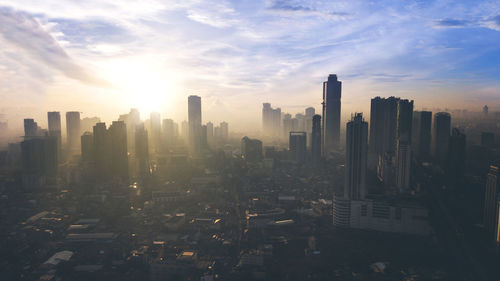 Aerial view of city buildings against sky during sunset