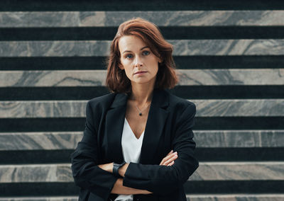 Portrait of young woman standing against steps