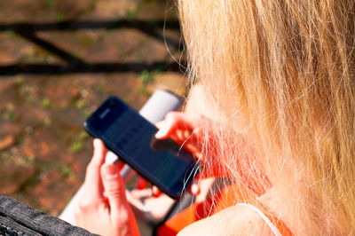 Close-up portrait of woman holding mobile phone outdoors