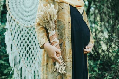 Midsection of woman holding umbrella standing by plants