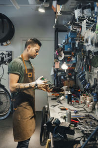 Mid adult male mechanic repairing bicycle pedal in workshop