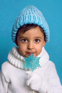 Baby boy eats a blue candy in the form of a snowflake