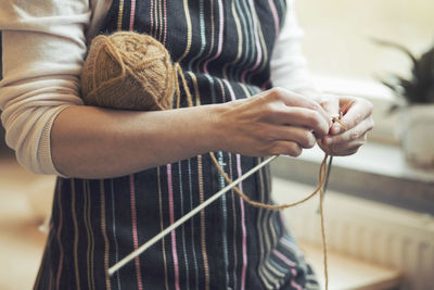 Midsection of woman knitting at home