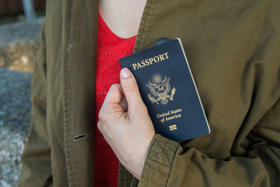 Close-up midsection of woman holding passport