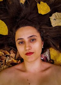 Portrait of young woman lying on autumn leaves