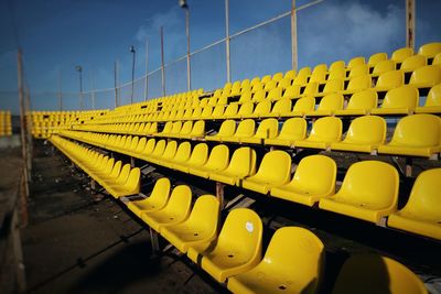 Yellow empty seats in row against sky at dusk