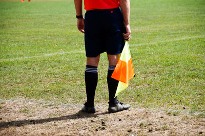 Low section of soccer player with flag standing on field