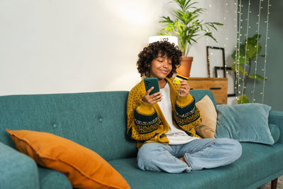 Young woman sitting on sofa at home