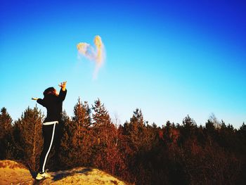 Man standing on field against clear blue sky