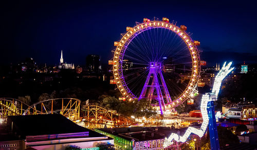 Illuminated amusement park in city at night