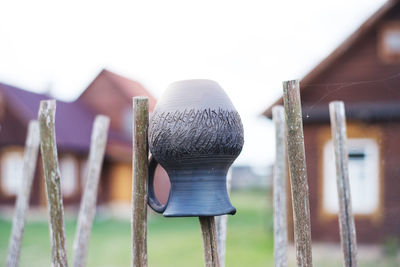 Close-up of pot on wooden post against clear sky