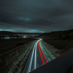 Light trails on highway against sky at night