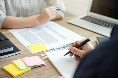 Midsection of colleagues working on office desk