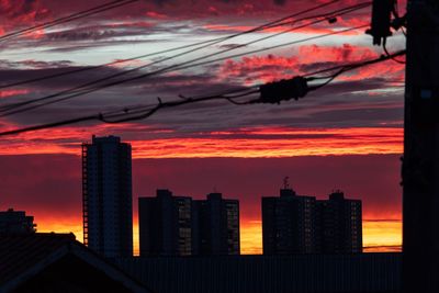 Silhouette buildings against dramatic sky during sunset