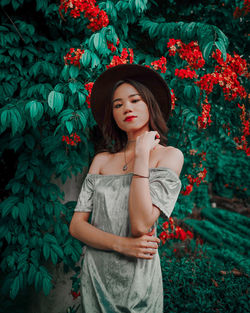 Full length of beautiful young woman standing against plants