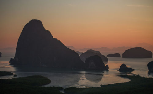 Scenic view of rocks in sea against sky during sunset