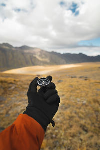 First-person view of a male traveler's hand holding a magnetic compass against