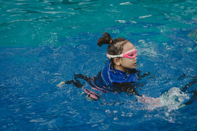 Children girl in swimming pool. wearing goggles and life jackets.