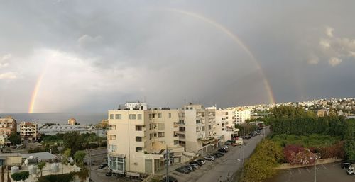 High angle view of rainbow over buildings in city against sky