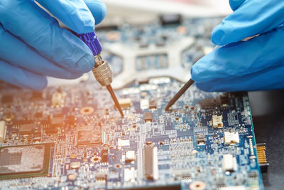 Close-up of hands working against blue sky