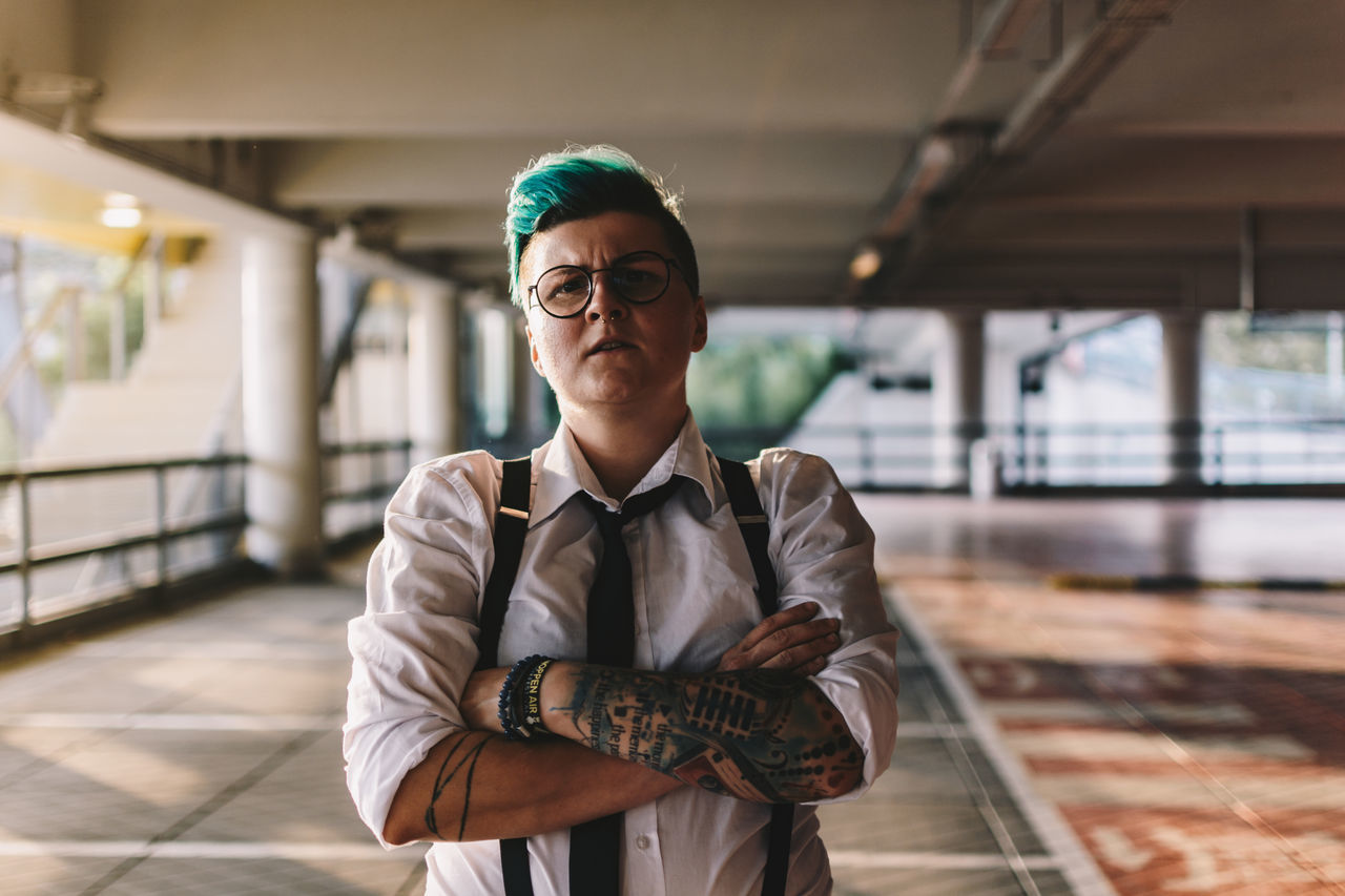 one person, portrait, eyeglasses, glasses, looking at camera, real people, front view, standing, focus on foreground, waist up, men, clothing, young adult, lifestyles, young men, males, mid adult, architecture