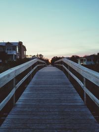 Footbridge against clear sky at sunset