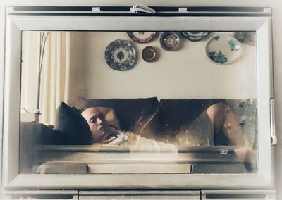 Portrait of man lying down on window