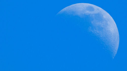 Low angle view of moon against blue sky