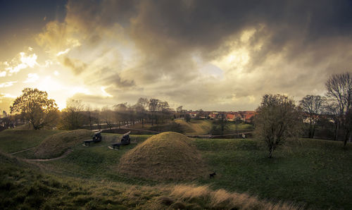 Scenic view of grassy field against cloudy sky during sunset