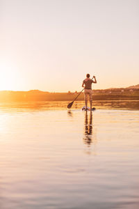 Man standing on beach against sky during sunset