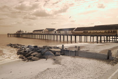 Pier on beach against sky during sunset