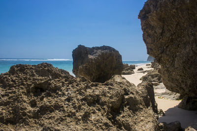 Rocks on beach against clear blue sky